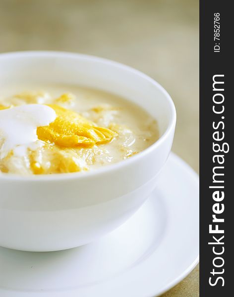 Durian dessert with sticky rice and coconut milk in a white bowl.