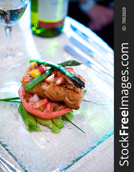 An image of fresh salmon on a bed of avocado and tomato topped with asparagus and fruit. An image of fresh salmon on a bed of avocado and tomato topped with asparagus and fruit