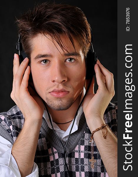 Man listening music in headphones. Black background. Studio shot.