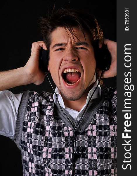 Man listening music in headphones. Black background. Studio shot.