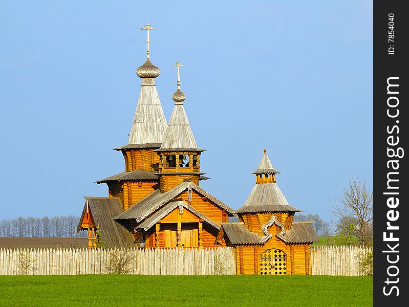 Beautiful wooden church in the field against the backdrop of a blue sky
