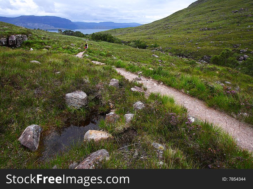 Trek path in the highlands (Scotland) with a water puddle at first plan