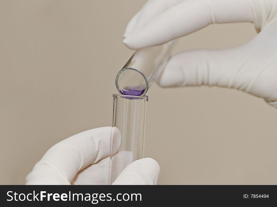Scientist fingers holding a glass test tube in a research lab. Scientist fingers holding a glass test tube in a research lab