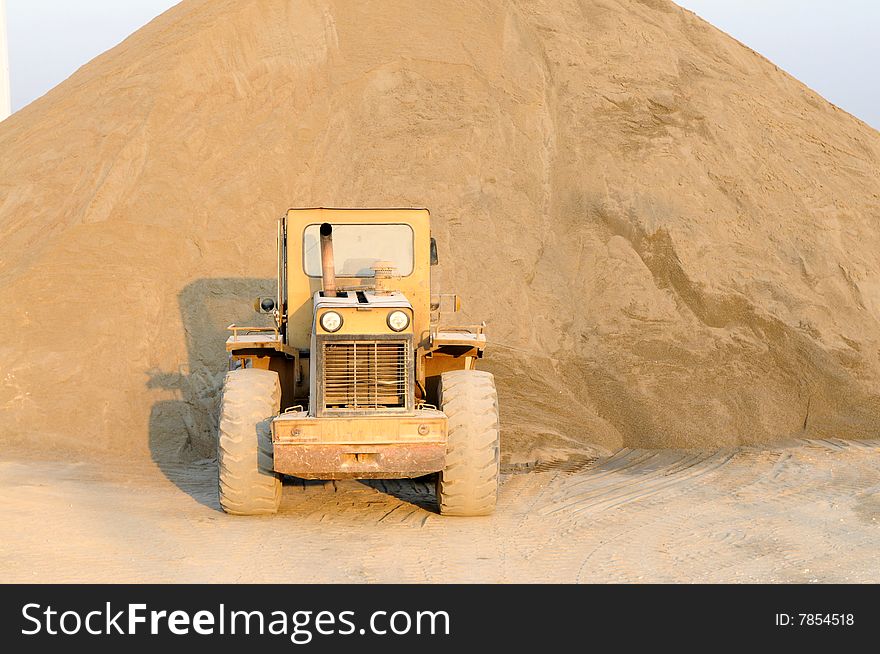 The bulldozer stopped before the sand heap in a sandpit. The bulldozer stopped before the sand heap in a sandpit.