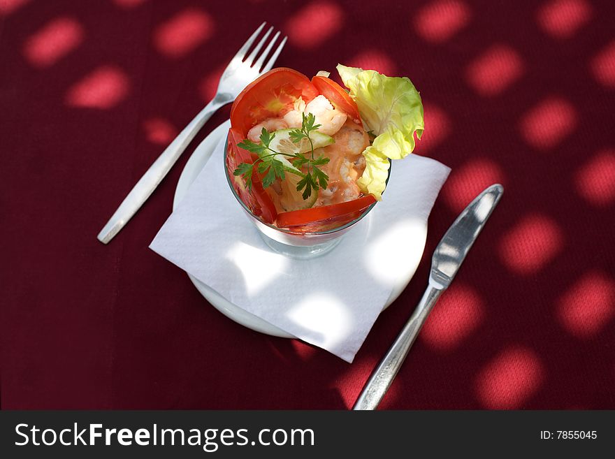 Prawn cocktail at red tablecloth with sunlight spots