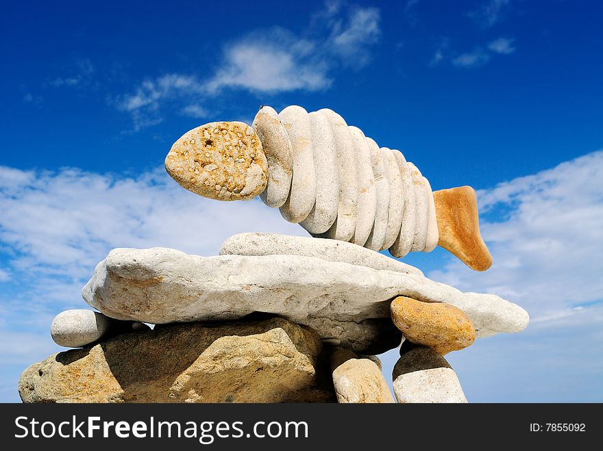 Pile of sea stones in the form of fish and the dark blue sky. Pile of sea stones in the form of fish and the dark blue sky