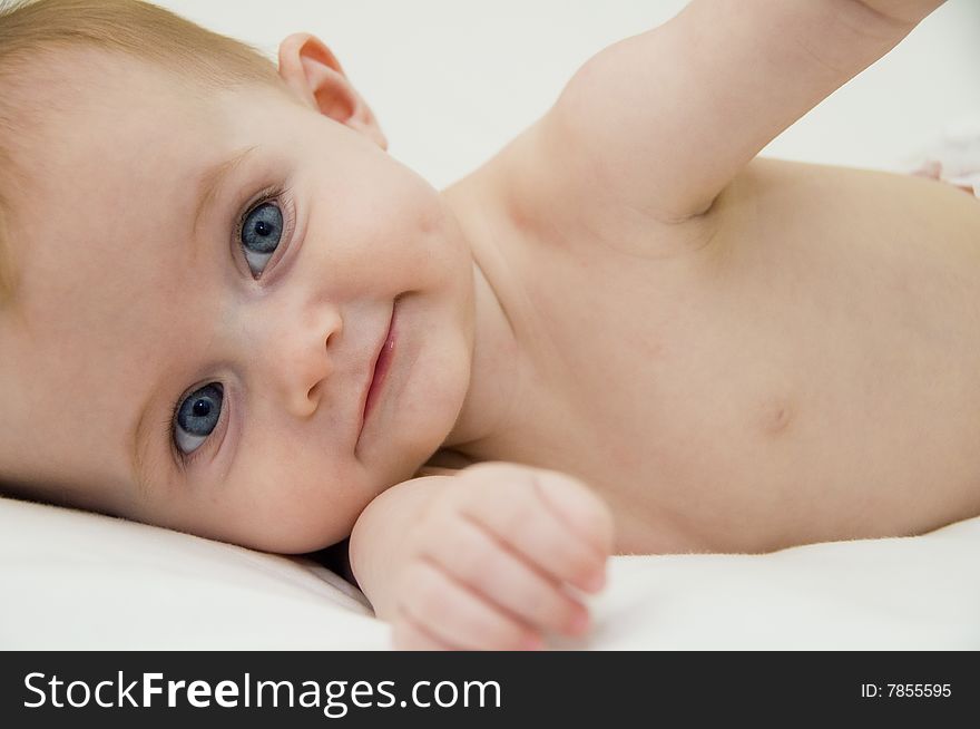 Cute baby girl playing on a bed with a white background