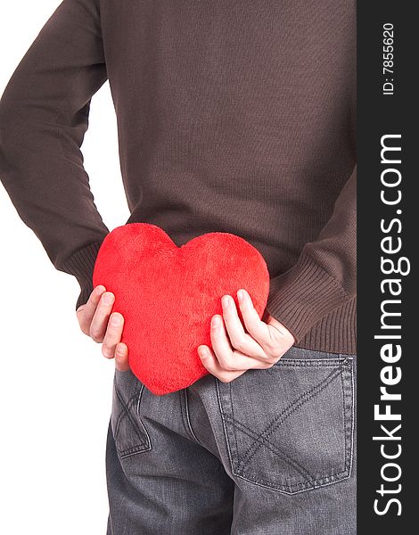 A young man holds a heart shaped pillow behind his back which he gives as a present to his girlfriend for valentines day. Isolated over white. A young man holds a heart shaped pillow behind his back which he gives as a present to his girlfriend for valentines day. Isolated over white.