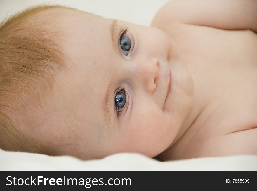 Cute baby girl playing on a bed with a white background