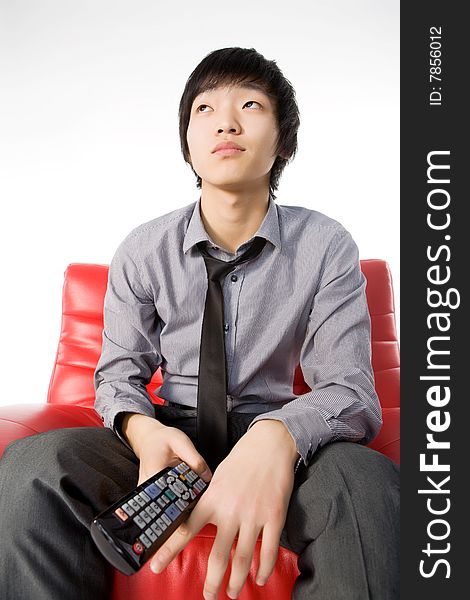 The smiling young man in a grey shirt watches TV