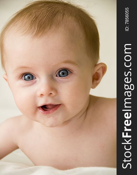 Cute baby girl playing on a bed with a white background