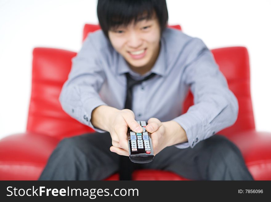 The smiling young man in a grey shirt watches TV