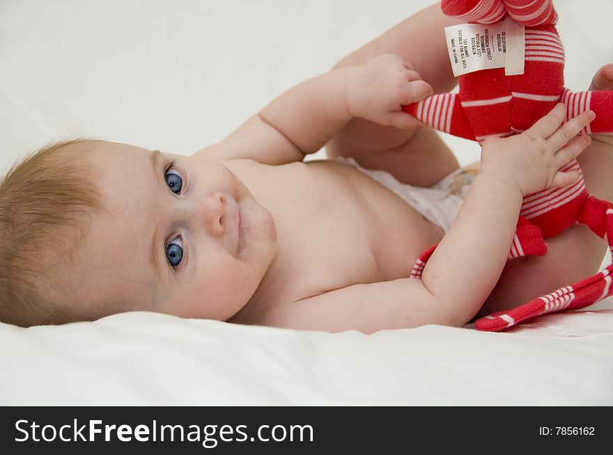 Cute baby girl playing on a bed with a white background