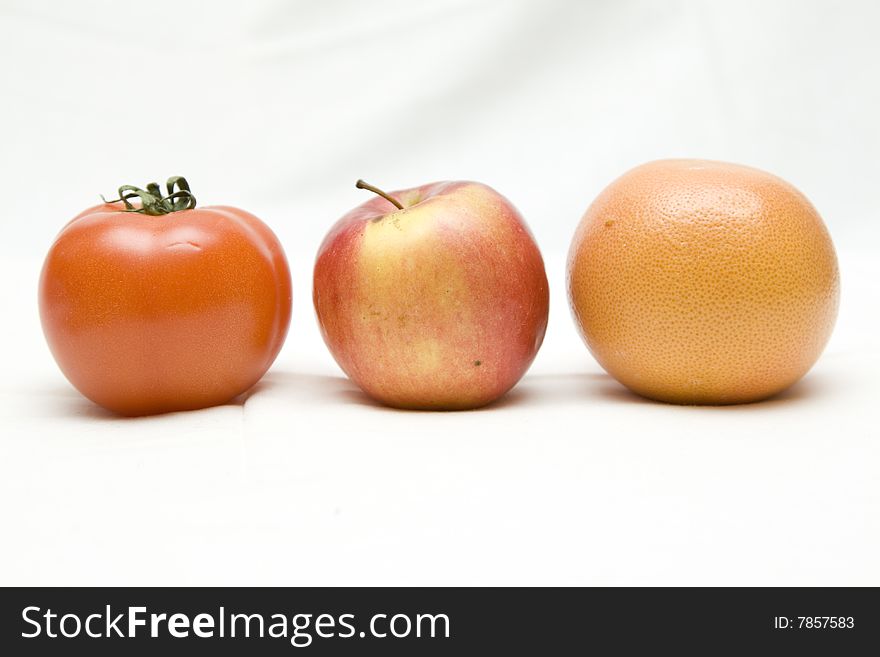 Apple, tomato and orange on the white not isolated background