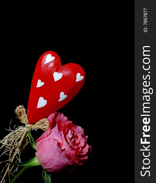 Red wooden heart and a  red rose isolated on black. Red wooden heart and a  red rose isolated on black.