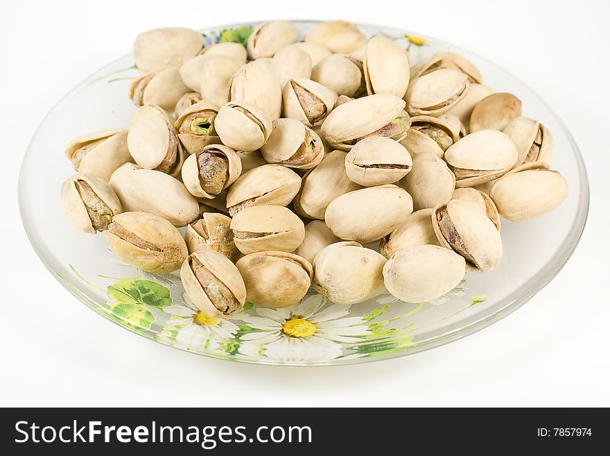 Pistachios on saucer with nutshell on white