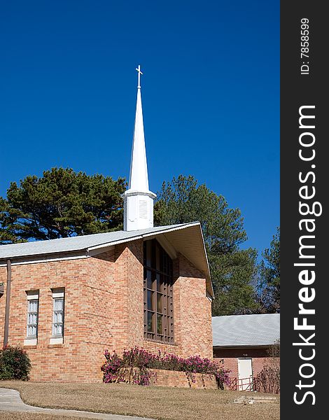 A small brick church and steeple against a blue sky. A small brick church and steeple against a blue sky