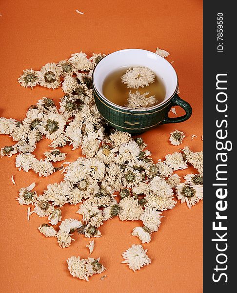 This is a cup of chrysanthemum tea in the orange background .