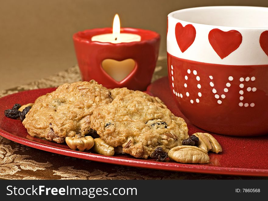 Oatmeal Raisin Cookies on a heart shaped plate with Valentines mug and candle. Oatmeal Raisin Cookies on a heart shaped plate with Valentines mug and candle