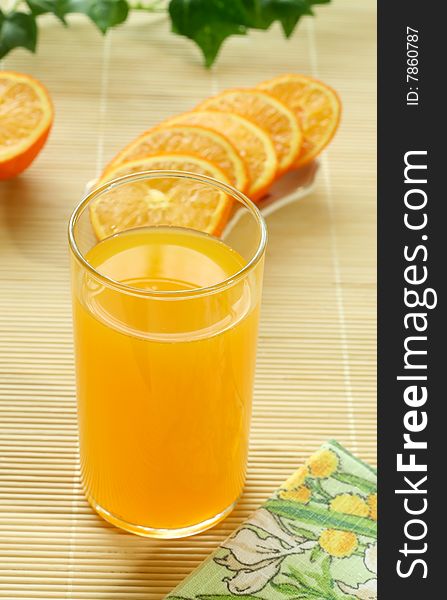 Orange juice in a glass and oranges, closeup