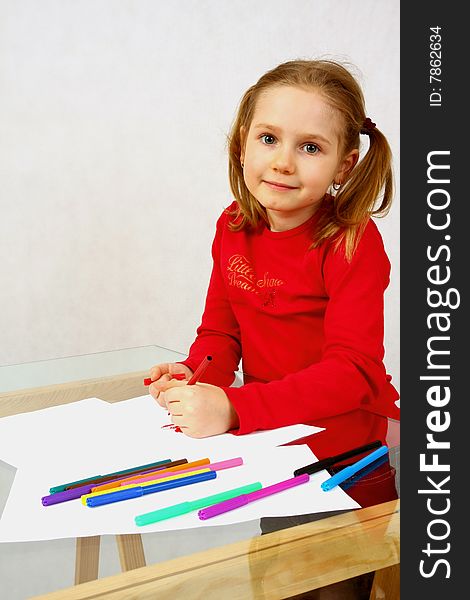 Young girl in red drawing an image with felt-pen. Isolated. Young girl in red drawing an image with felt-pen. Isolated.