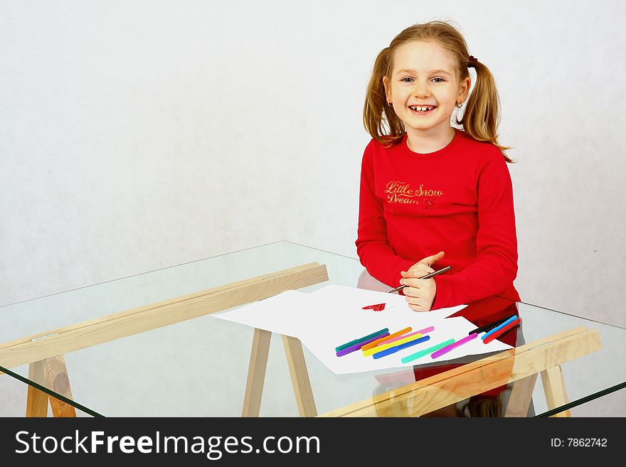 Young girl in red drawing an image with felt-pen. Isolated. Young girl in red drawing an image with felt-pen. Isolated.