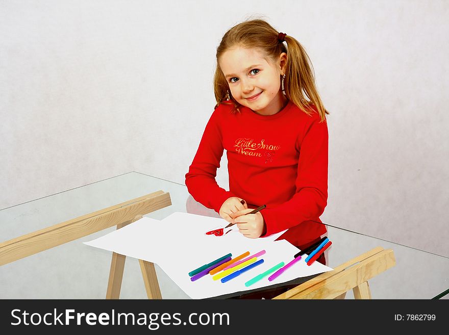 Young girl in red drawing an image with felt-pen. Isolated. Young girl in red drawing an image with felt-pen. Isolated.