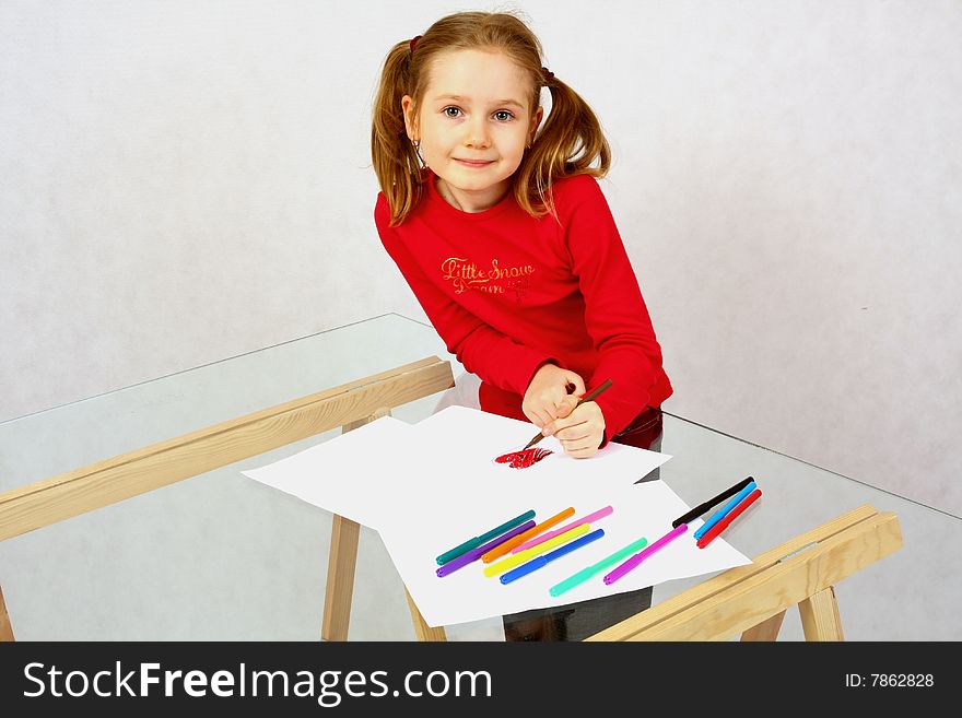 Young girl in red drawing an image with felt-pen. Isolated.