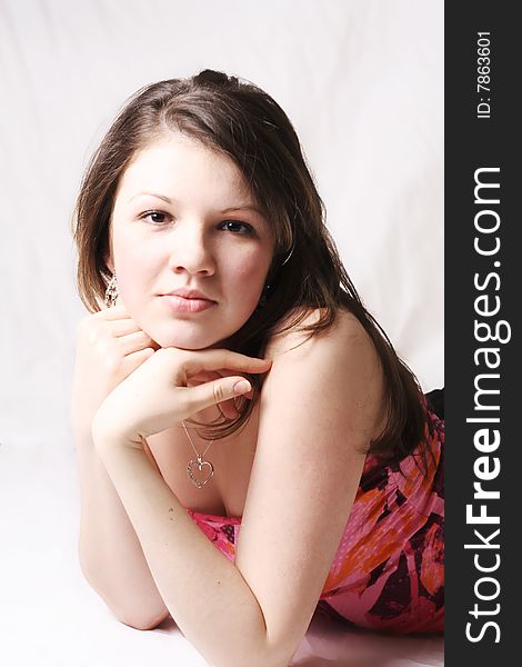 Teen girl  on white soft background wearing a colorful dress looking straight into the camera and smiling. Teen girl  on white soft background wearing a colorful dress looking straight into the camera and smiling