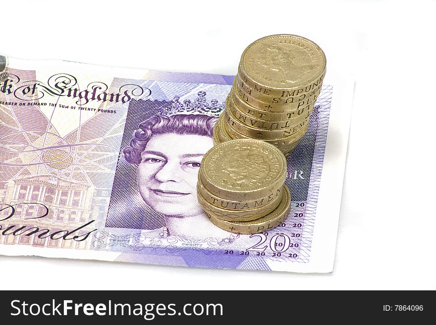British twenty pound note with a pile of pound coins. British twenty pound note with a pile of pound coins