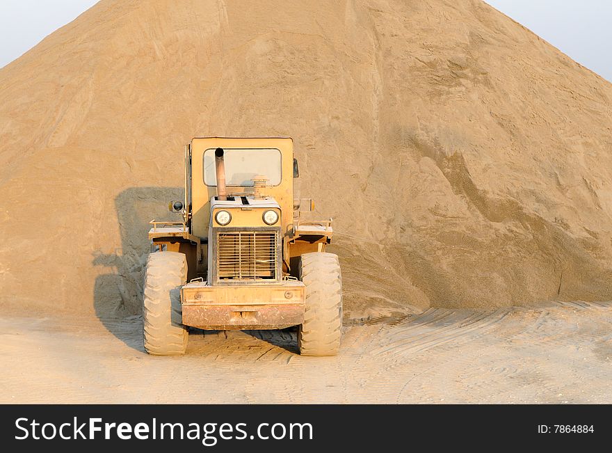 The bulldozer in a construction site before a sand heap. The bulldozer in a construction site before a sand heap.