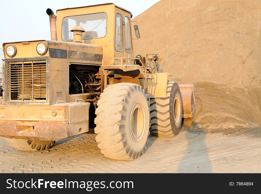 The old bulldozer stops before a sand heap. The old bulldozer stops before a sand heap.