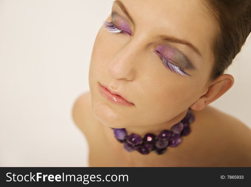 Headshot of beautiful, young female with colorful eye make-up and beaded necklace. Headshot of beautiful, young female with colorful eye make-up and beaded necklace.