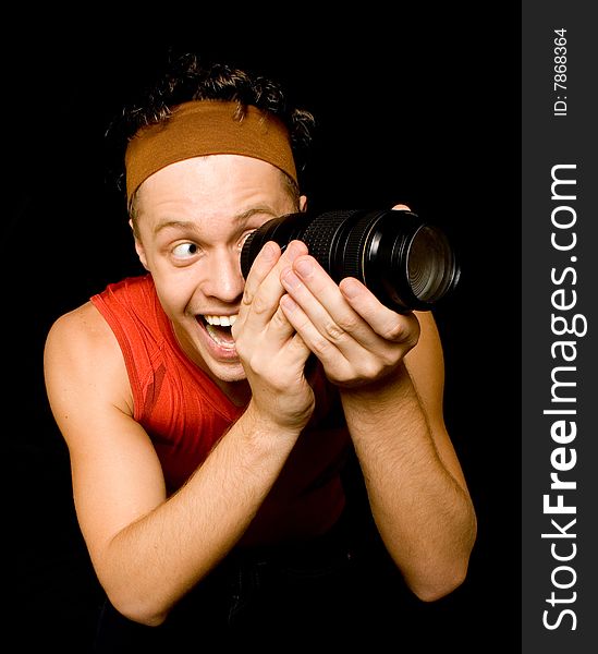 Young man looks through camera lens over black