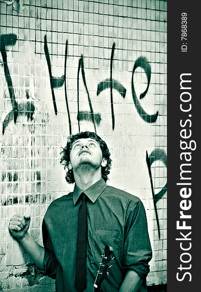 Monochrome lomo picture of business styled man with guitar over brick wall with graffiti