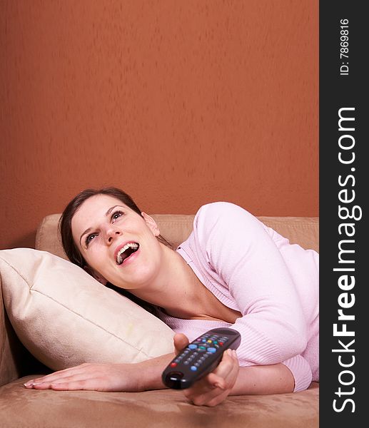 A young woman sits in front of a TV with the remote control in her hand on a couch. A lot of copyspace left. A young woman sits in front of a TV with the remote control in her hand on a couch. A lot of copyspace left.