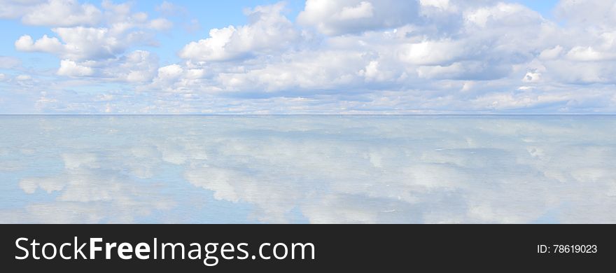 Heavenly blue sky reflected on lakeside horizon.