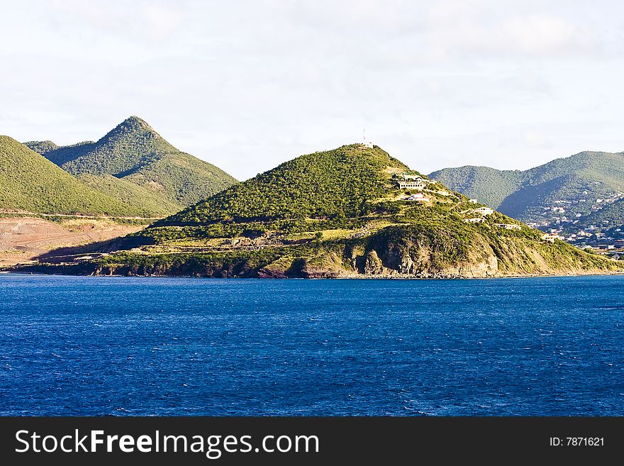 The coast off a tropical island with green islands rising from the blue sea. The coast off a tropical island with green islands rising from the blue sea