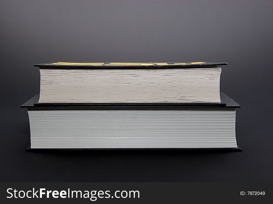 Two thick black books isolated on black background. Two thick black books isolated on black background