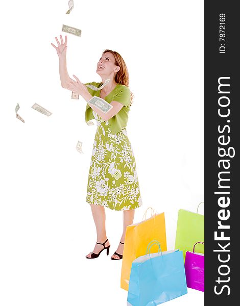 Young woman standing with a pile of shopping bags and grabbing money from the air. Young woman standing with a pile of shopping bags and grabbing money from the air