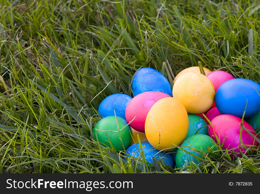 Stack of brightly colored easter eggs sitting in the grass