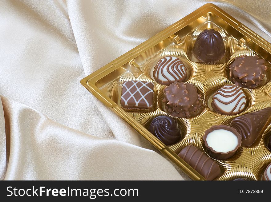 Variety of chocolate candies sitting on cream silk