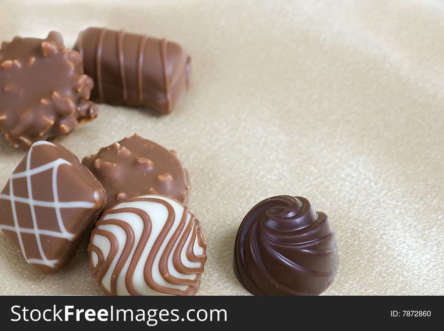 Chocolate candies laid out as a border on ivory satin