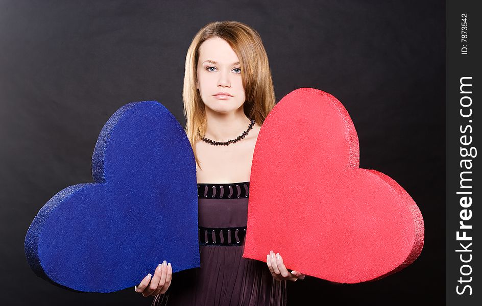 Pretty girl portrait with two hearts  over black background