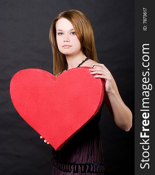 Girl holding red heart  over black background
