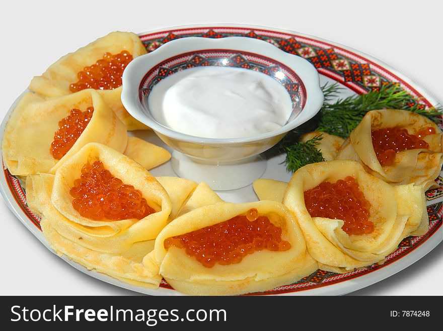 Pancakes with red caviar on a plate with the Ukrainian ornament