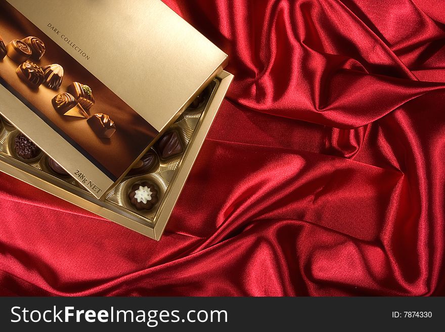 Golden chocolates box on red satin background