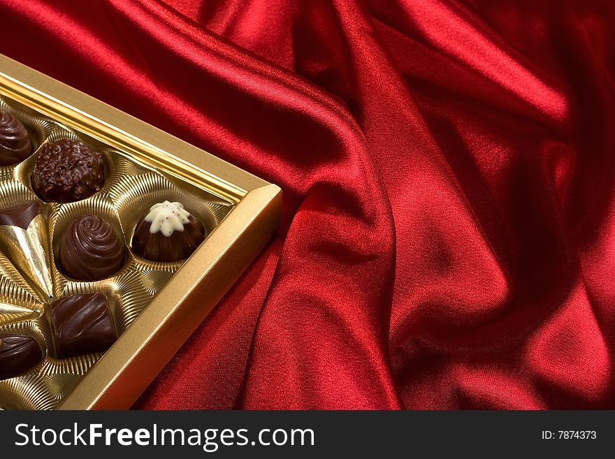 Golden chocolates box on red satin background