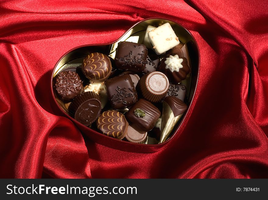 Heart Shaped Box Of Candy On Red Satin Background