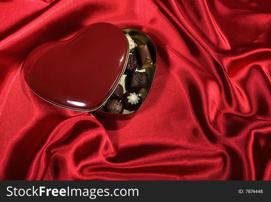 Heart Shaped Box Of Candy On Red Satin Background